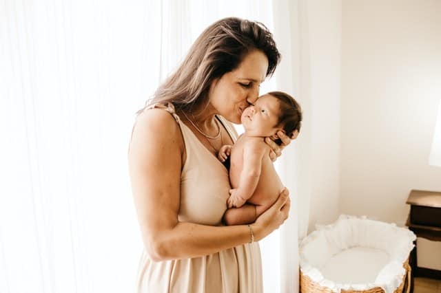 mother kissing newborn