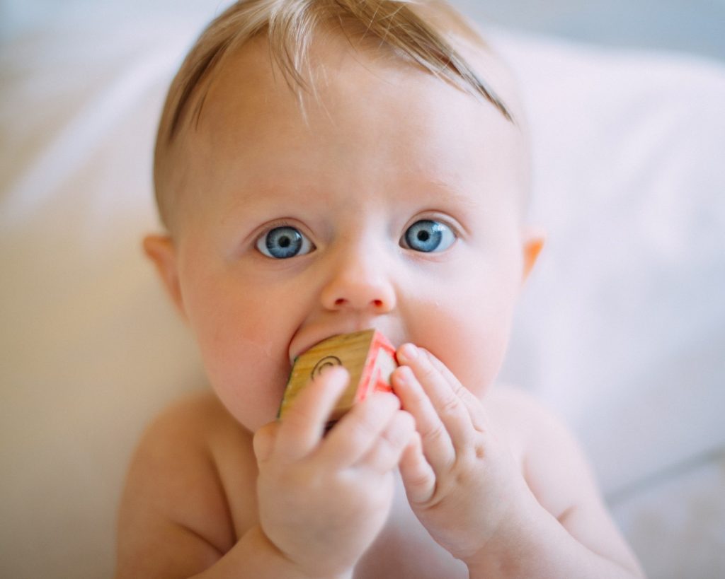 baby chewing on a wooden block