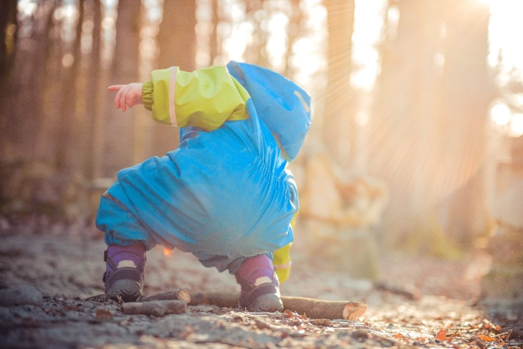 baby picking up a wood