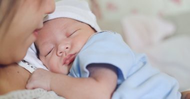 baby sleeping on mother's arms