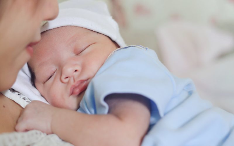 baby sleeping on mother's arms