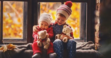 girl with her baby brother holding teddy bear