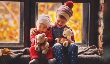 girl with her baby brother holding teddy bear