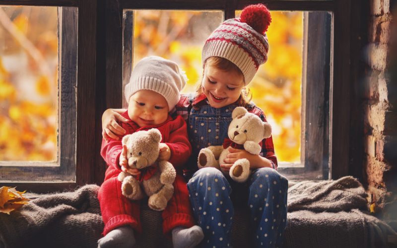 girl with her baby brother holding teddy bear
