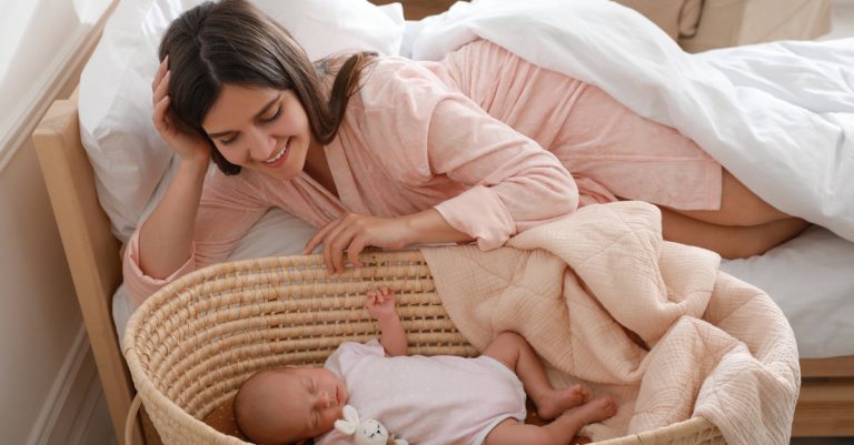 mom smiling over her baby on a bassinet