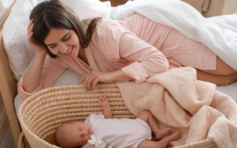mom smiling over her baby on a bassinet