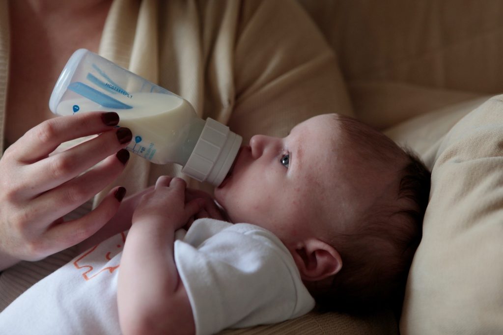 mother feeding her baby with bottled milk