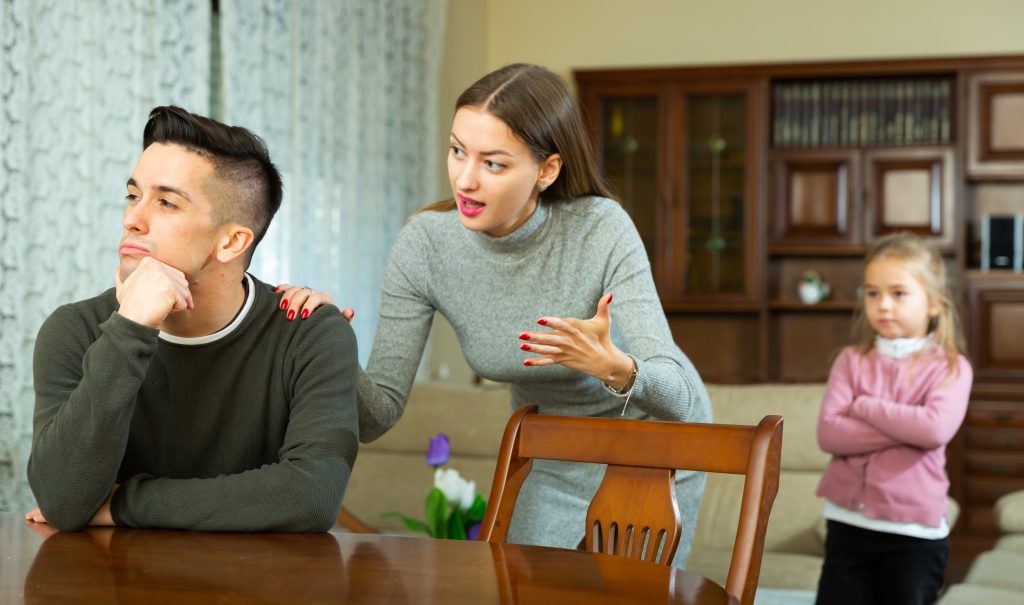 woman explaining something to a man while little girl crosses her arm