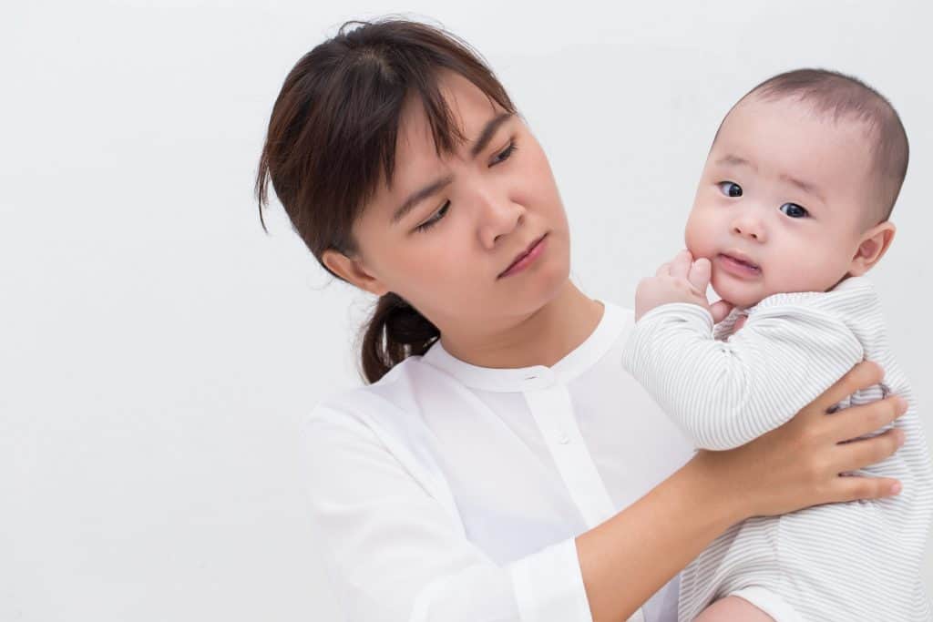 annoyed mother looking at her baby