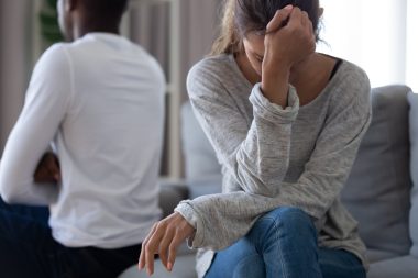 disappointed woman sitting on couch with partner