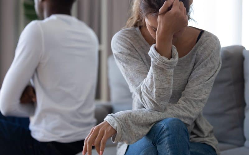 disappointed woman sitting on couch with partner
