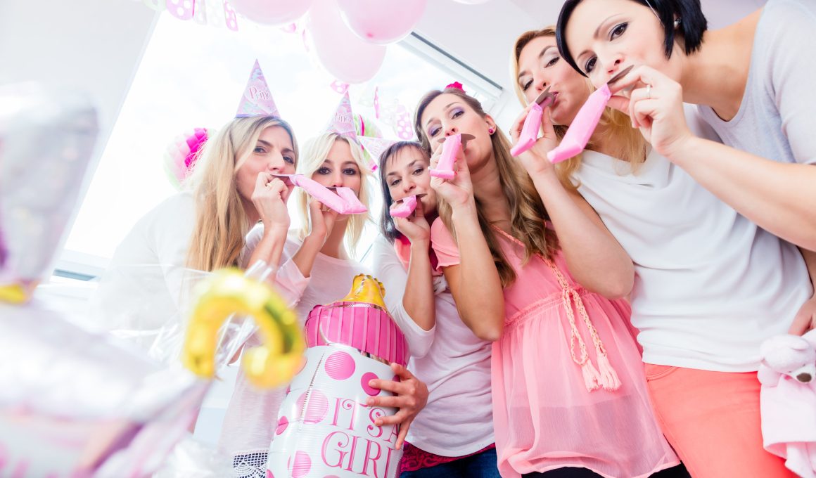 women blowing balloons on baby shower