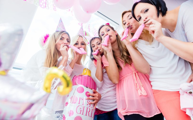 women blowing balloons on baby shower