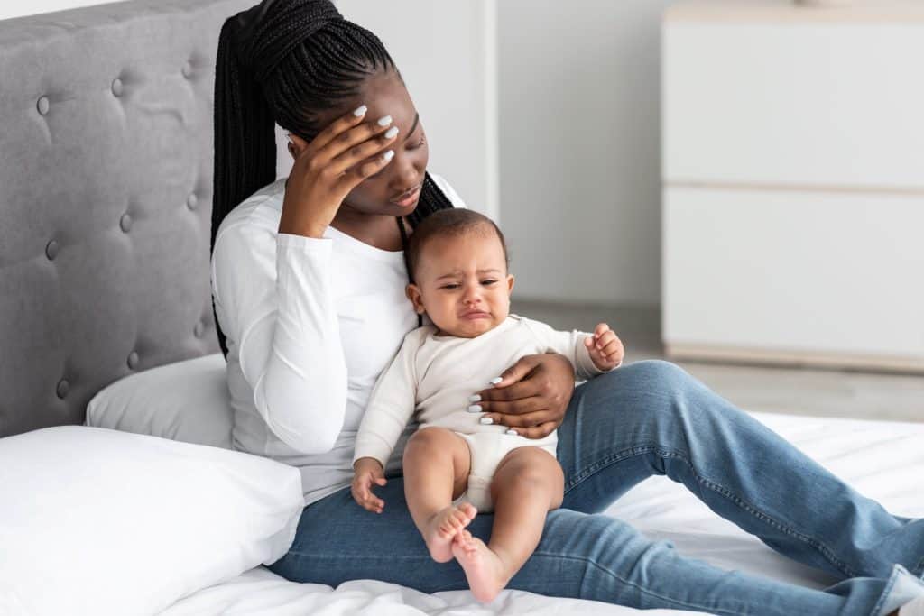 frustrated mom holding her baby in bed