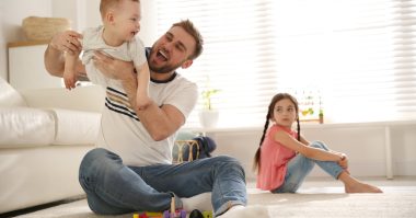 jealous girl while dad is playing with baby