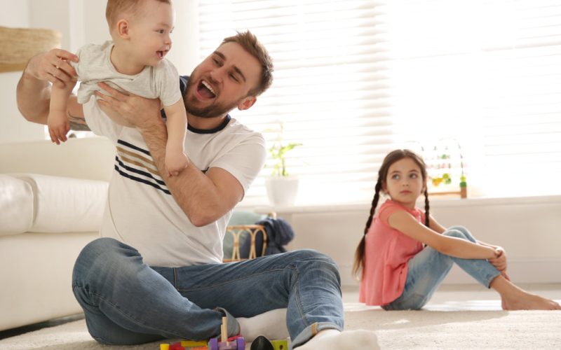 jealous girl while dad is playing with baby