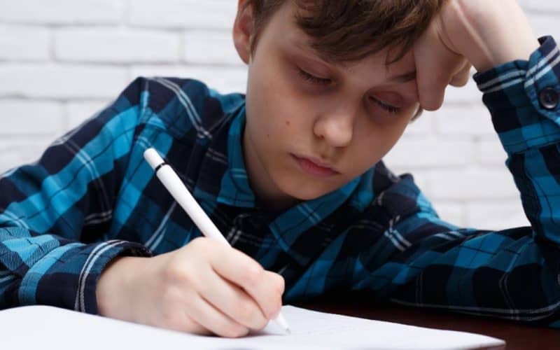 little boy falling asleep while studying