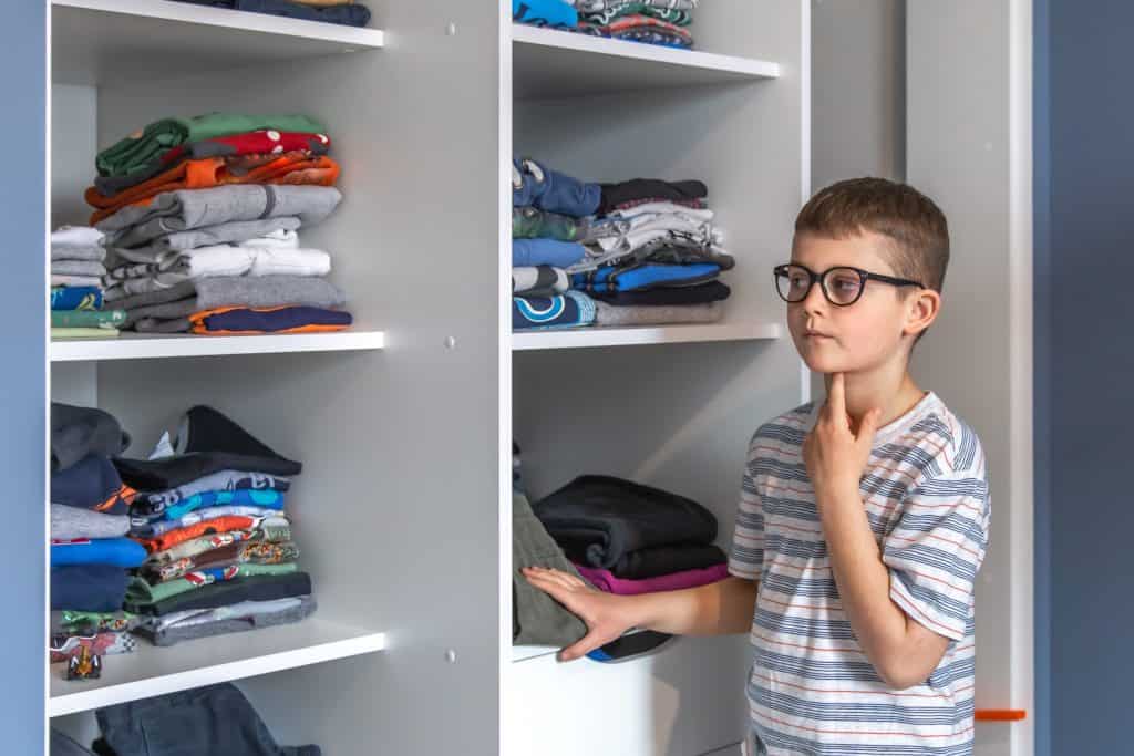 little boy looking at folded clothes