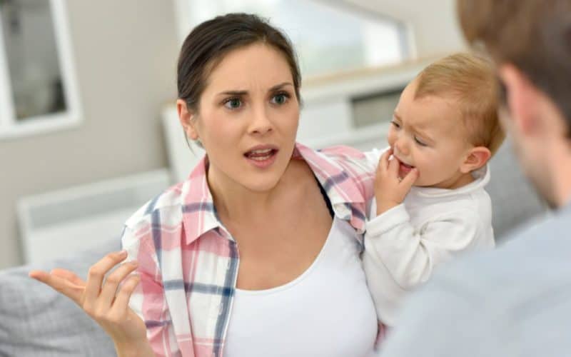 man and woman arguing in front of baby