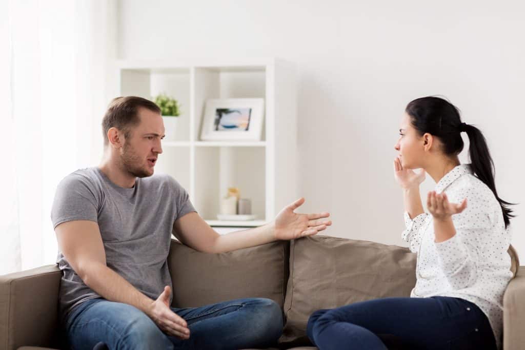man and woman arguing on the couch