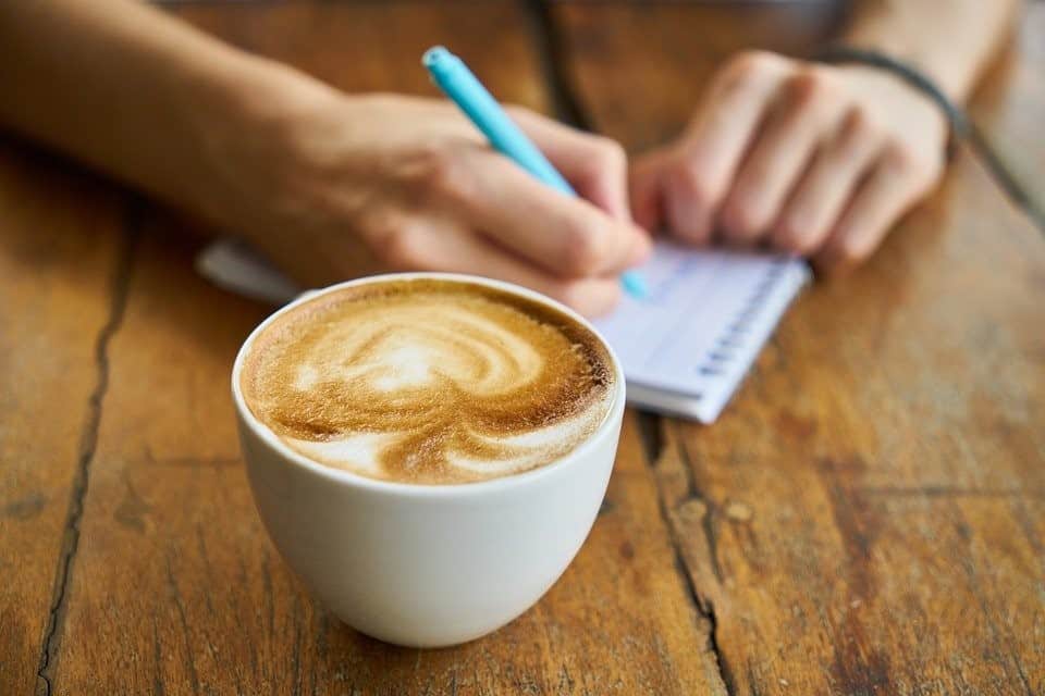 man talking notes with coffee on the table