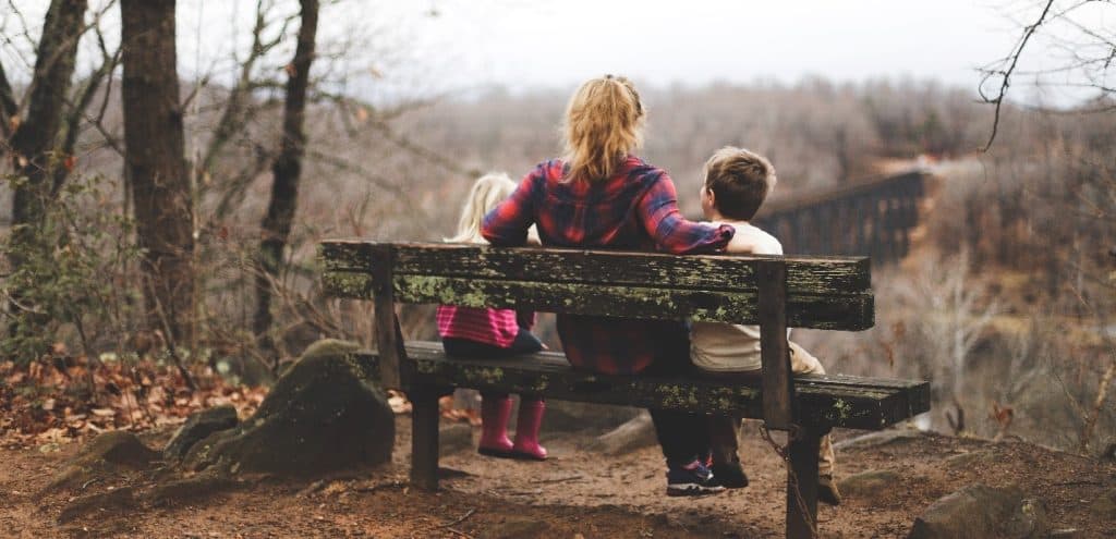 mom sitting on a bench with her two child