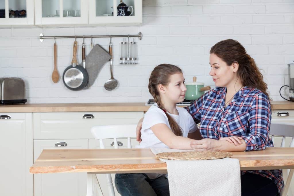 mother hugging little girl in the kitchen