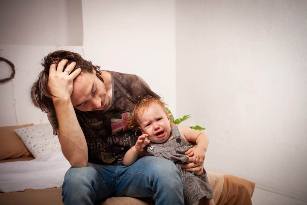 tired dad holding his crying baby