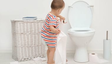 toddler playing with toilet paper in the bathroom