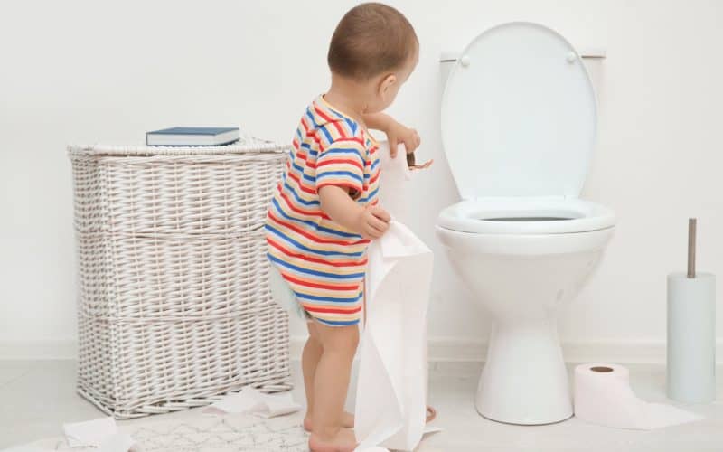 toddler playing with toilet paper in the bathroom