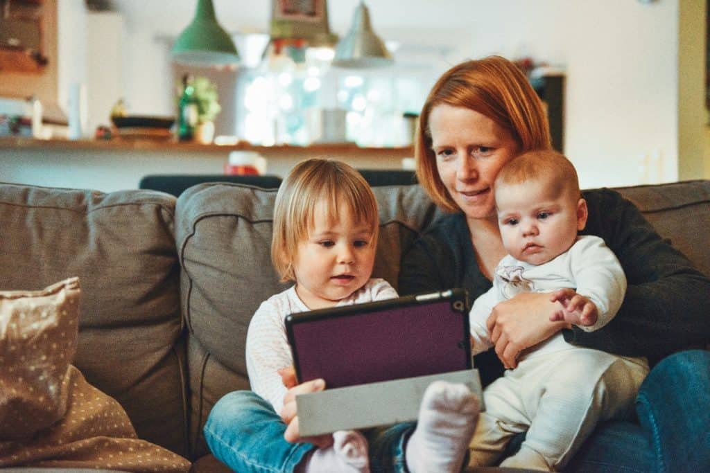 woman and two babies looking at an ipad