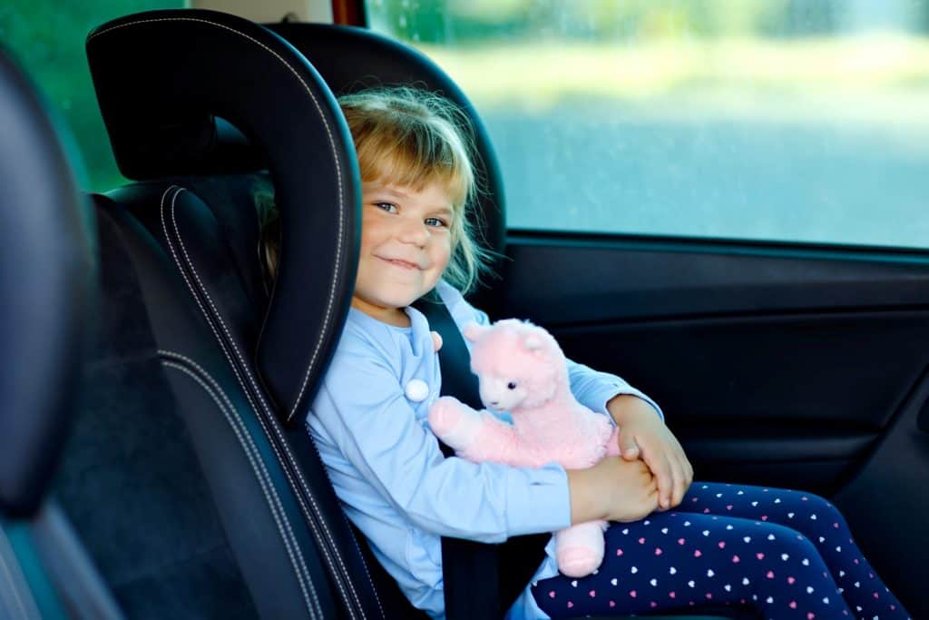 baby girl smiling in the car holding a pink llama
