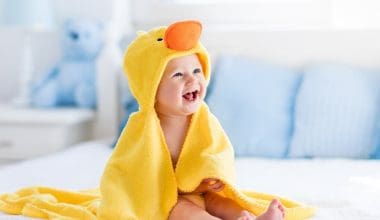 baby laughing wearing a duck towel