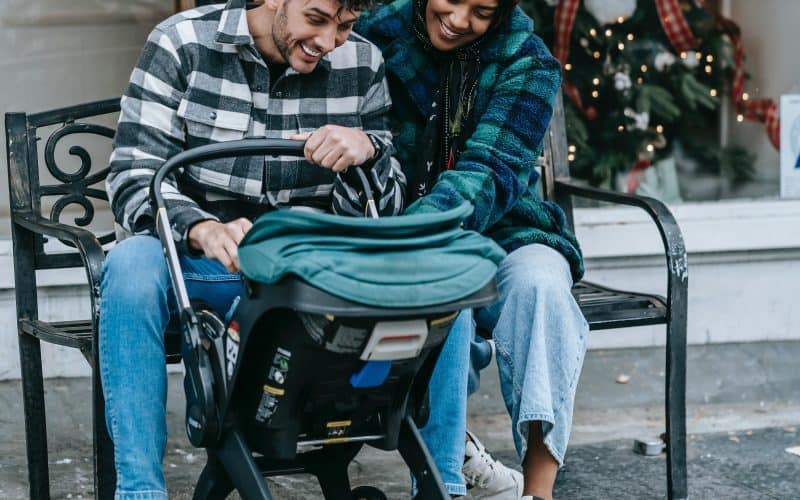 couple smiling at baby while on a stroller