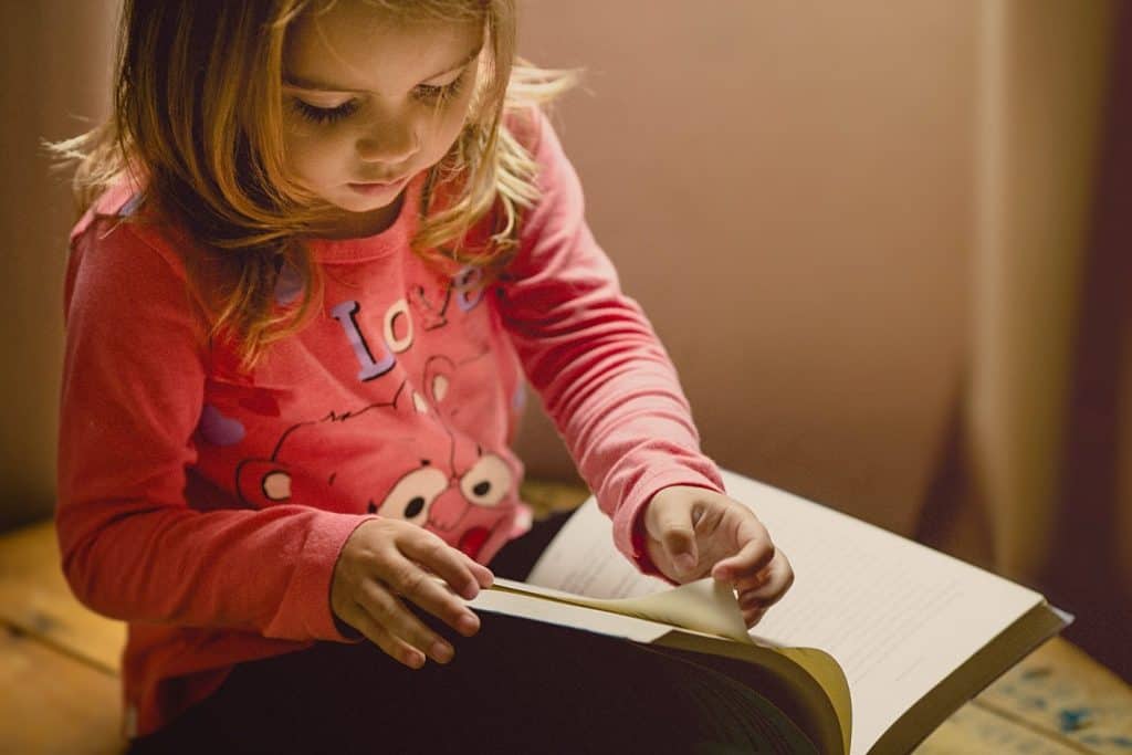 little girl leafing through a notebook