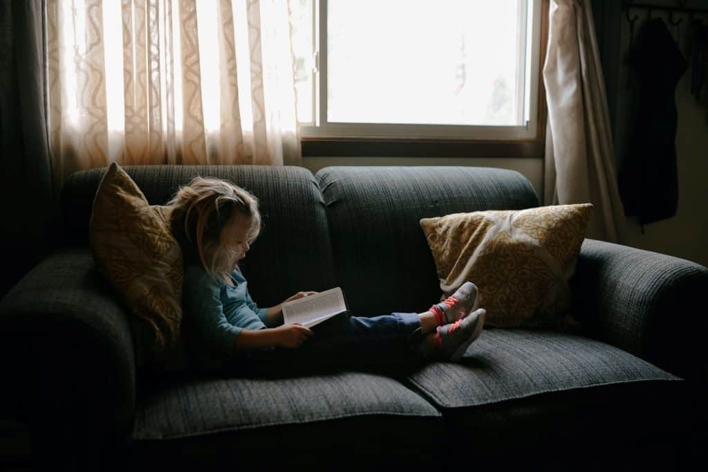 little girl reading at a couch