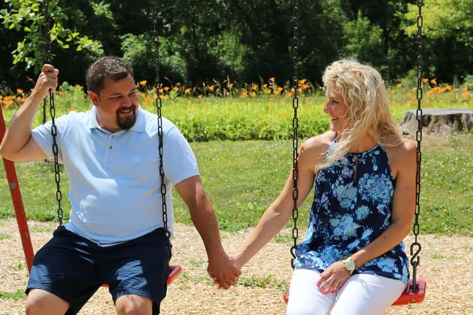 man and woman holding hands at a swingset