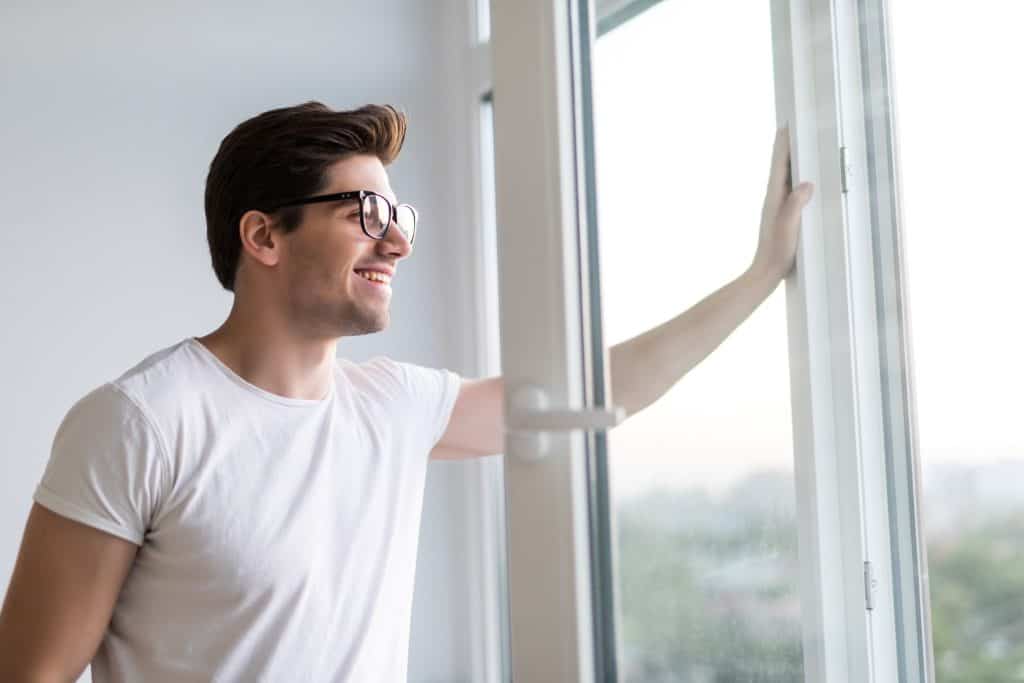 man smiling while looking out glass window