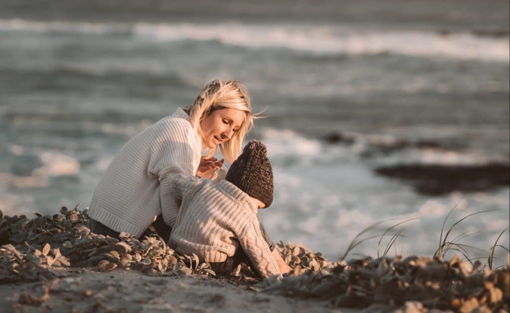 mom talking to her toddler on the shore