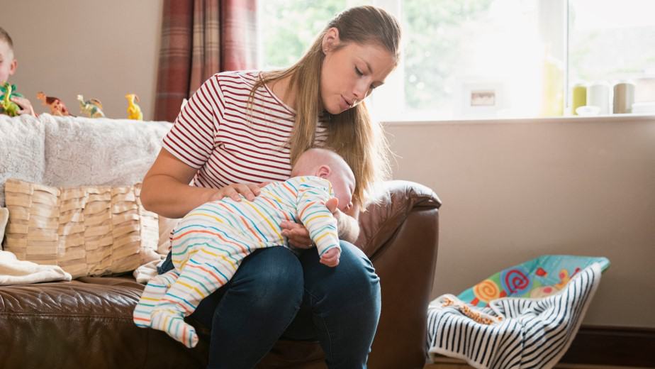 mother burping baby while on her lap