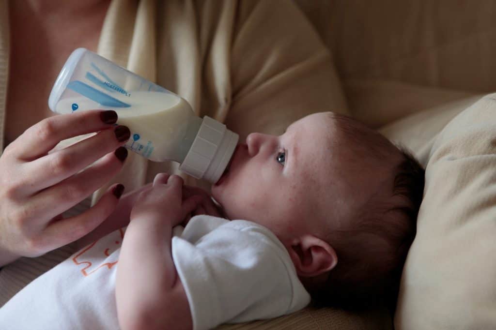 mother feeding milk bottle to baby