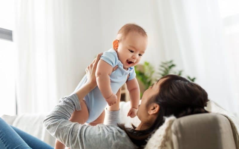 mother holding her baby up the air