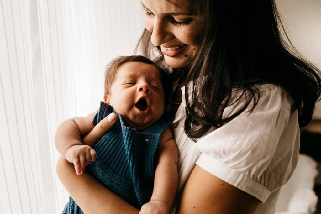 mother smiling at baby yawning