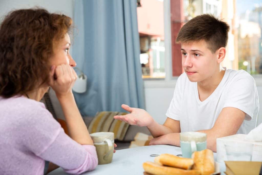teenage boy talking to his mom in the dining table