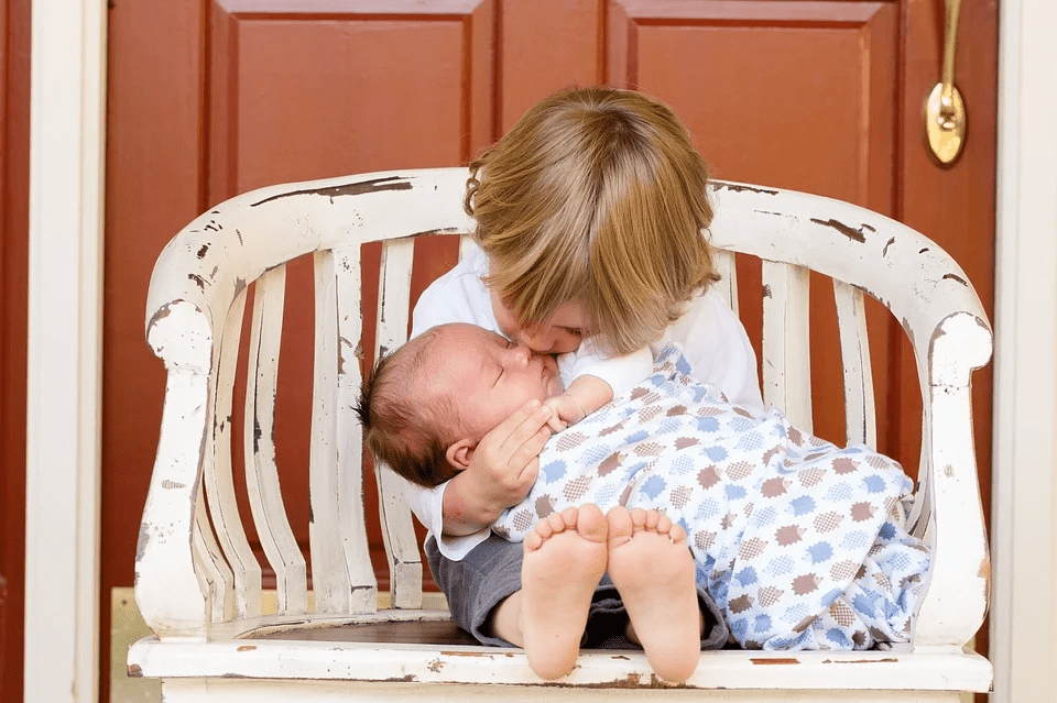 toddler kissing newborn baby