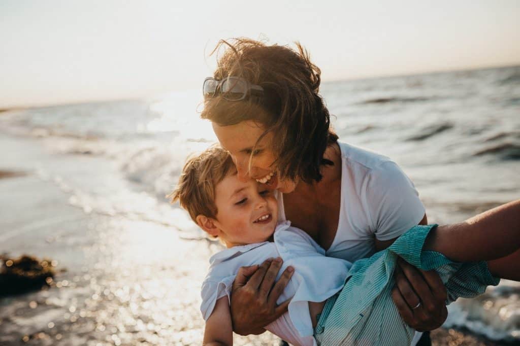 woman carrying a child at the beach