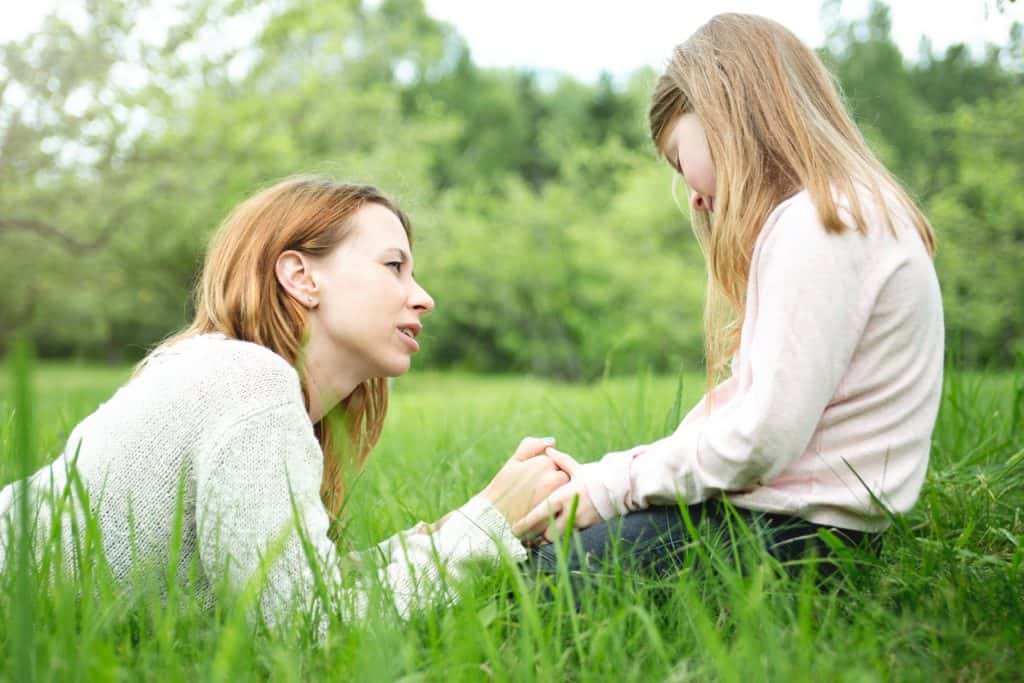 woman talking to her kid on a grass