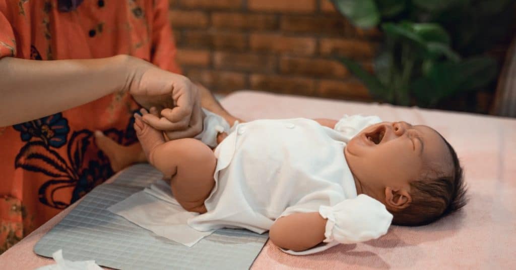 baby crying while mother changes his diaper