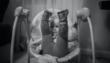 baby lifting her feet up while on a baby swing