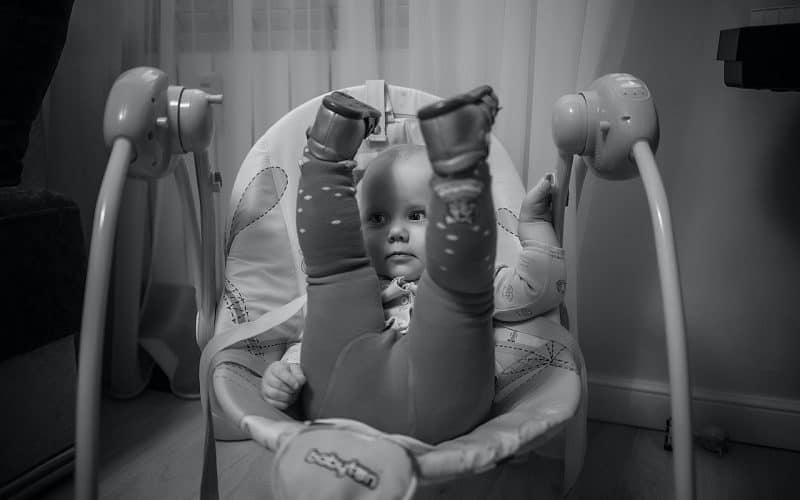 baby lifting her feet up while on a baby swing